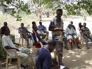 Edem taking notes while a farmer raises his concerns.