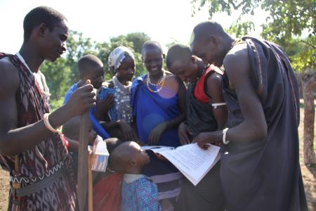 Maasai reading educational booklet.